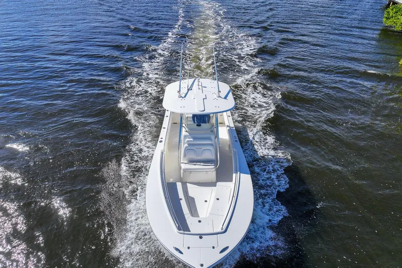 Slide: The Image of 2014 Regulator 25 boat cruising on a sunny day near a golf course. - 7