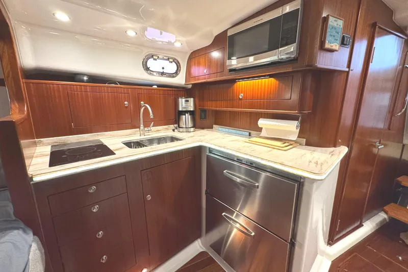 Slide: The Image of 2019 Pursuit OS 385 Offshore yacht kitchen with modern appliances and wood cabinetry. - 10