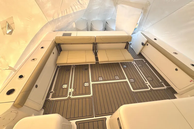 Slide: The Image of 2019 Pursuit OS 385 Offshore boat interior with beige seating and wood-patterned flooring. - 19