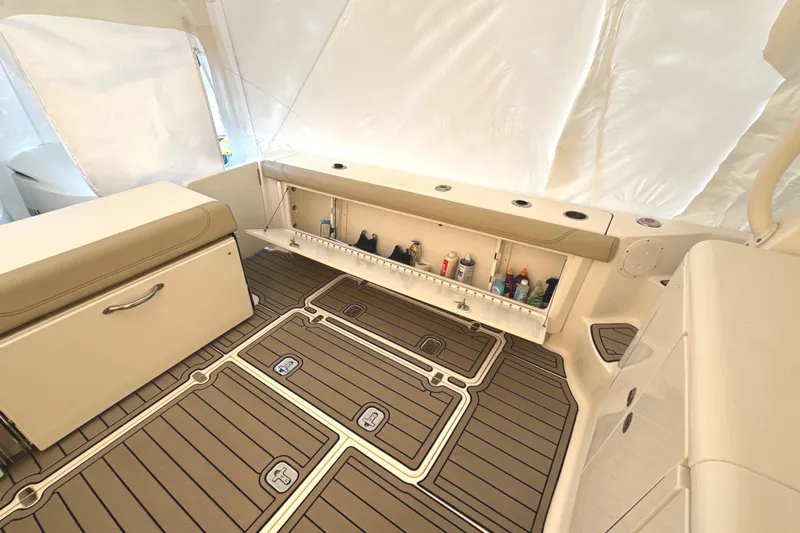 Slide: The Image of 2019 Pursuit OS 385 Offshore interior with storage compartment and cushioned seating. - 22