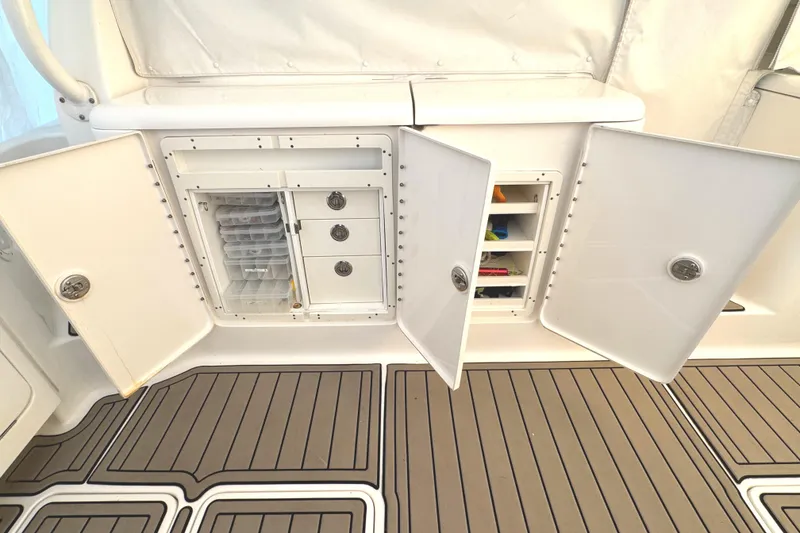 Slide: The Image of 2019 Pursuit OS 385 Offshore boat storage compartments with open doors, revealing organized shelves. - 23