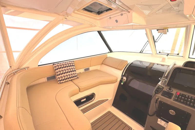 Slide: The Image of 2019 Pursuit OS 385 Offshore interior with beige seating and modern helm controls. - 24