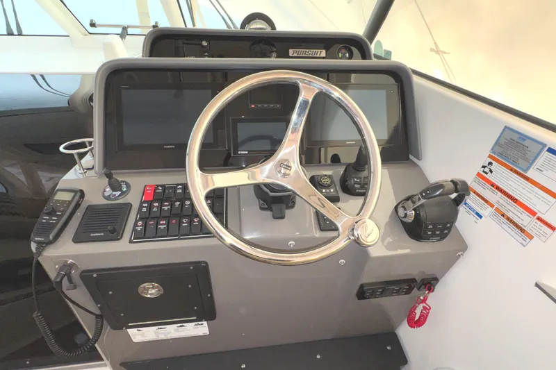 Slide: The Image of 2019 Pursuit OS 385 Offshore helm with steering wheel and navigation controls. - 31