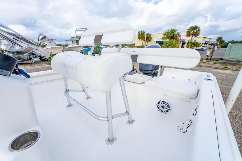 Slide: The Image of 2013 Tidewater 1900 Bay Max boat interior with white seating and console, parked outdoors. - 17