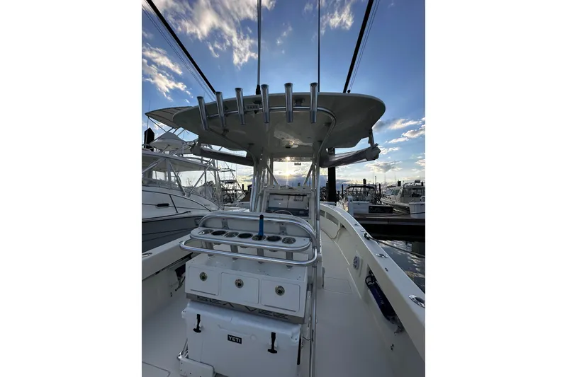 Slide: The Image of 2014 SeaVee 290B boat interior with fishing rod holders at marina, under a blue sky. - 4