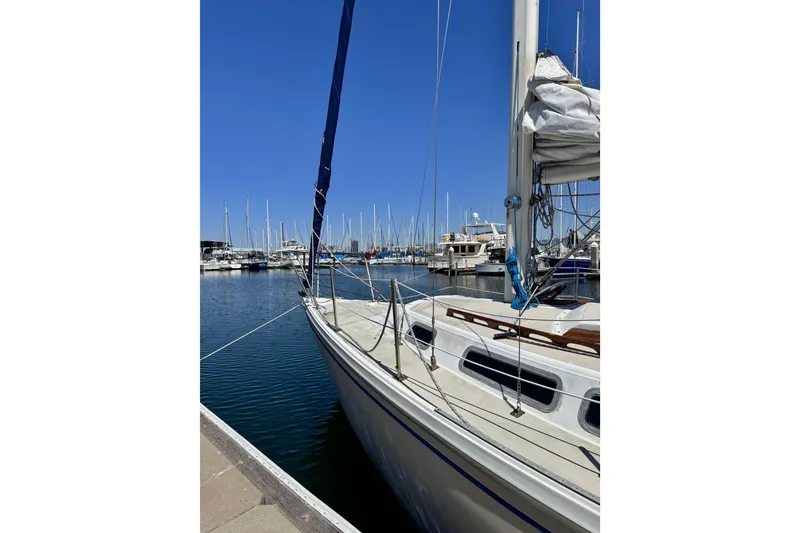 Slide: The Image of 1980 Catalina 30 sailboat docked at marina under clear blue sky. - 6