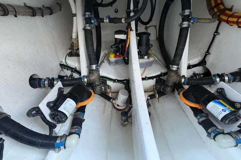 Slide: The Image of Engine compartment of 2023 Nor-Tech 340 Sport Open Center Console boat, showcasing intricate plumbing and wiring. - 14