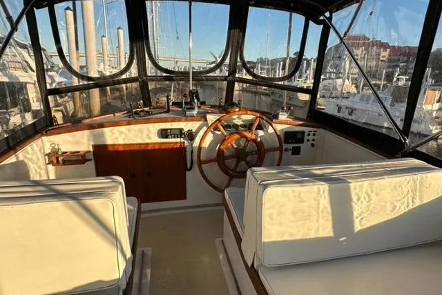 Slide: The Image of 1981 Grand Banks 36 Classic yacht interior with helm, wooden wheel, and white seating. - 12