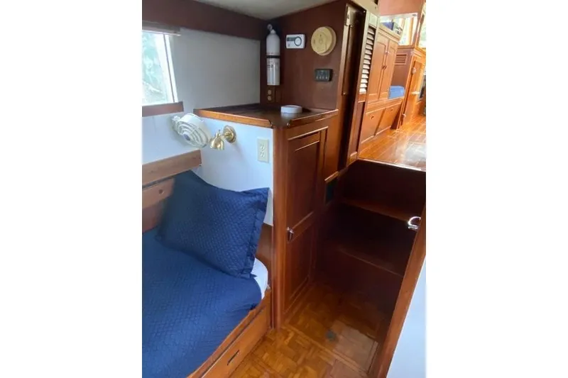 Slide: The Image of Interior of 1981 Grand Banks 36 Classic yacht with wooden cabinetry and blue bedding. - 36