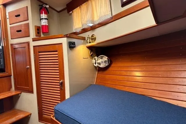 Slide: The Image of 1981 Grand Banks 36 Classic cabin interior with wooden paneling and blue bedding. - 41