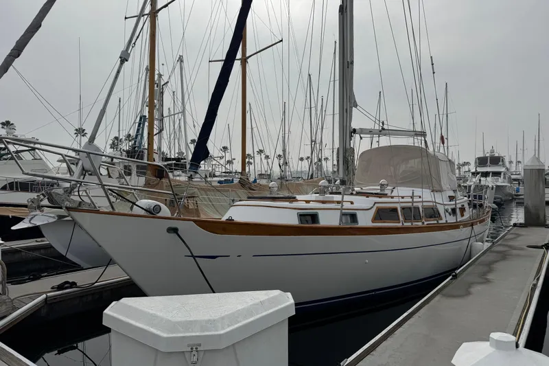 The Image of 1978 Robert Perry 47 sailboat docked at marina under a partly cloudy sky. - 0