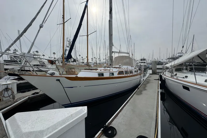 Slide: The Image of 1978 Robert Perry 47 sailboat docked at marina, showcasing sleek design and polished anchor. - 2