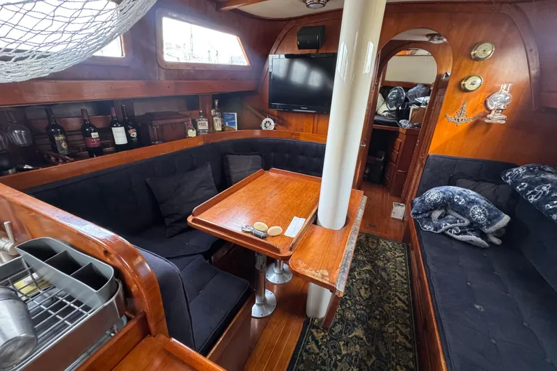 Slide: The Image of Cozy interior of a 1978 Robert Perry 47 yacht with wooden furnishings and plush seating. - 24
