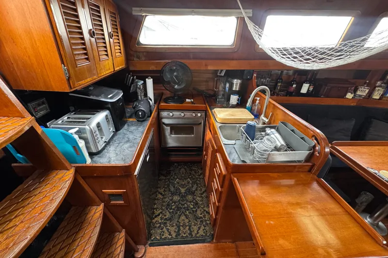 Slide: The Image of Cozy interior of 1978 Robert Perry 47 sailboat with wooden furnishings and seating area. - 25