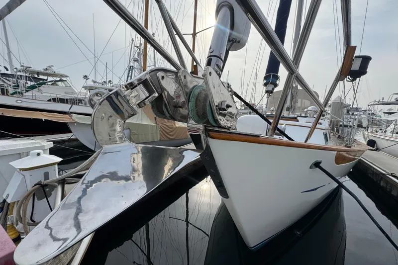 Slide: The Image of 1978 Robert Perry 47 sailboat docked, featuring polished anchor and wooden trim. - 4