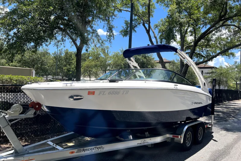 The Image of 2022 Regal LS2 boat on trailer, parked outdoors under trees. - 0