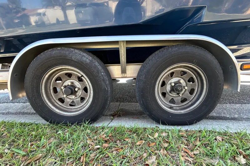 Slide: The Image of 2022 Regal LS2 trailer wheels on pavement with grass nearby. - 123