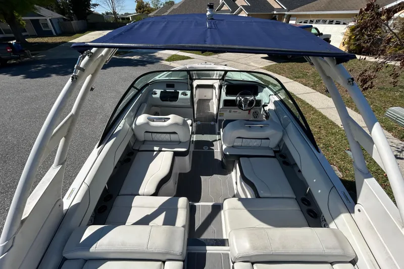 Slide: The Image of 2022 Regal LS2 boat interior with white seating and blue canopy, parked in a residential area. - 21