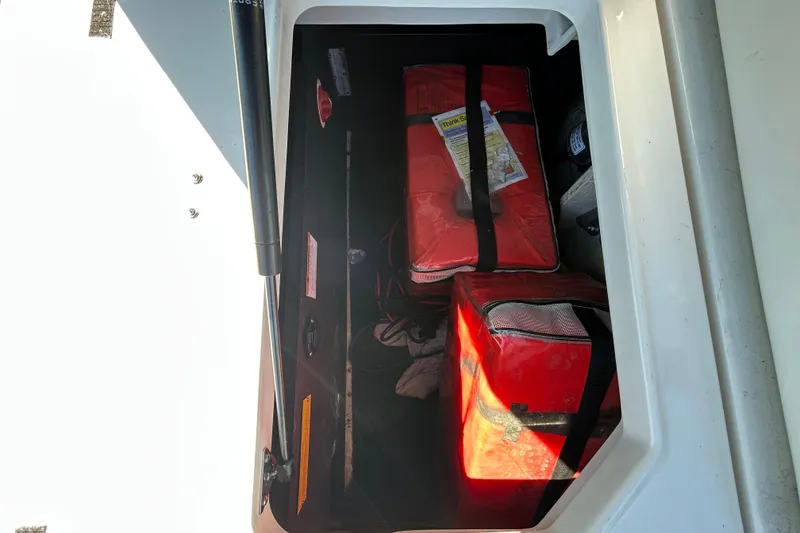 Slide: The Image of Storage compartment in a 2022 Regal LS2 boat with red safety equipment. - 53