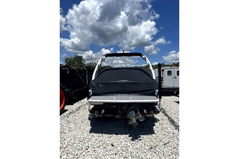 Slide: The Image of 2022 Regal LS2 boat with cover, parked on gravel under a cloudy sky. - 6