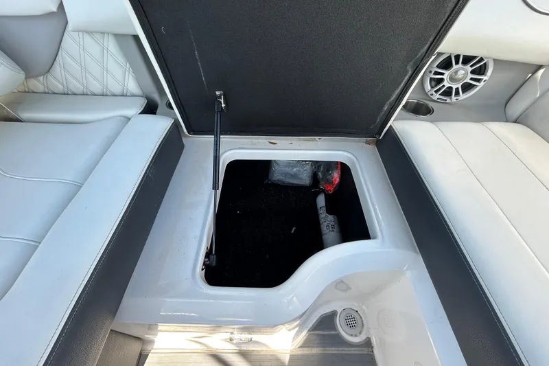 Slide: The Image of Open storage compartment in 2022 Regal LS2 boat, featuring white and black seating. - 72