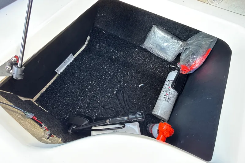 Slide: The Image of Storage compartment in a 2022 Regal LS2 boat with safety equipment and accessories. - 73