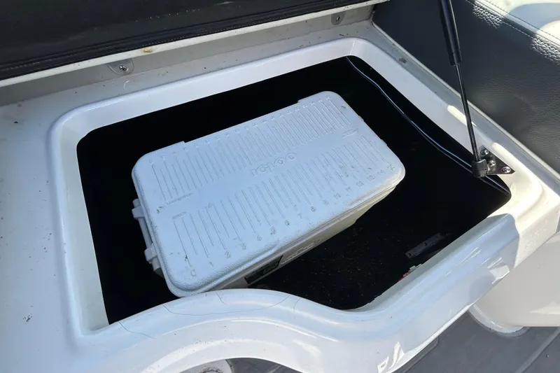 Slide: The Image of Storage compartment in a 2022 Regal LS2 boat with a white cooler inside. - 76
