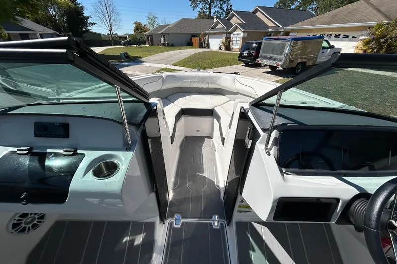 Slide: The Image of 2022 Regal LS2 boat interior with seating, cup holder, and dashboard in a residential driveway. - 86
