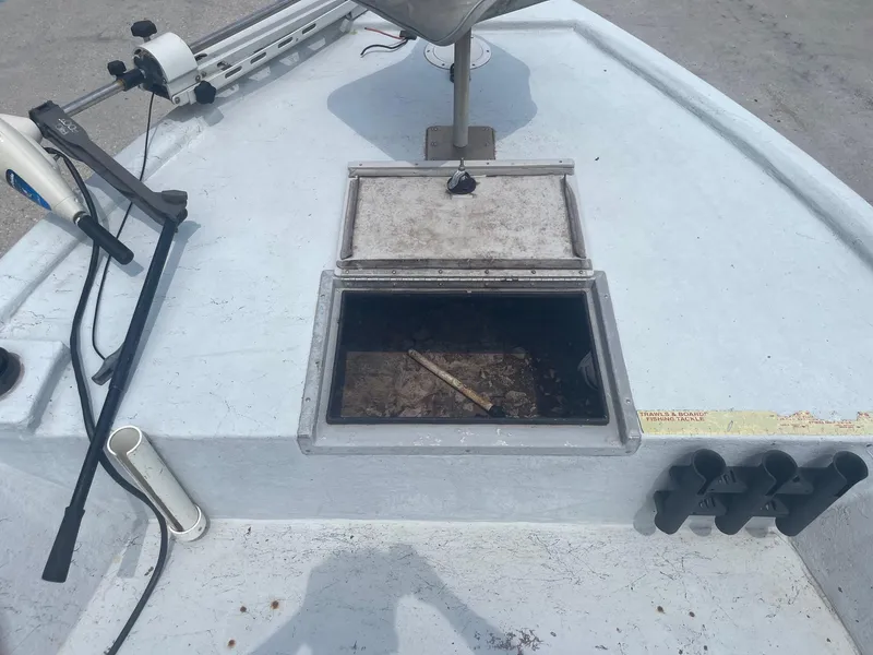 Slide: The Image of 2002 Champion 230-RV boat deck with open storage compartment and fishing rod holders. - 11