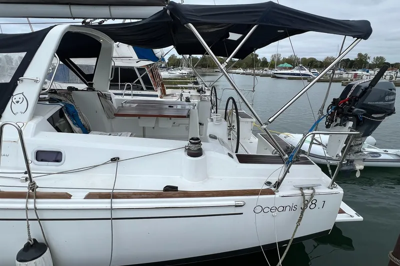 Slide: The Image of 2017 Beneteau Oceanis 38.1 sailboat docked, featuring dual steering wheels and a Yamaha outboard motor. - 6