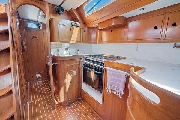 Slide: The Image of 1989 Wauquiez Centurion 47 yacht interior with wooden cabinetry and modern kitchen amenities. - 10