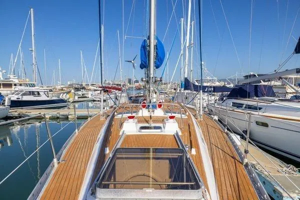 Slide: The Image of 1989 Wauquiez Centurion 47 sailboat docked in a marina, showcasing teak deck and mast. - 3