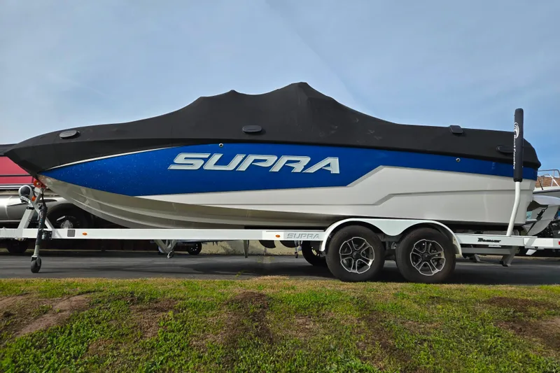 Slide: The Image of 2023 Supra SL 450 boat on trailer, covered, with blue and white design. - 7