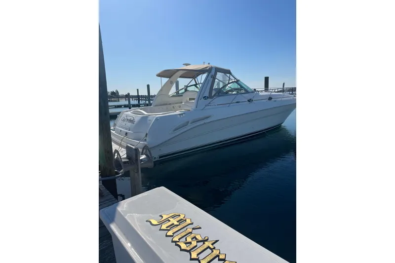 The Image of 2002 Sea Ray 410 Sundancer yacht docked at a marina under clear blue skies. - 0