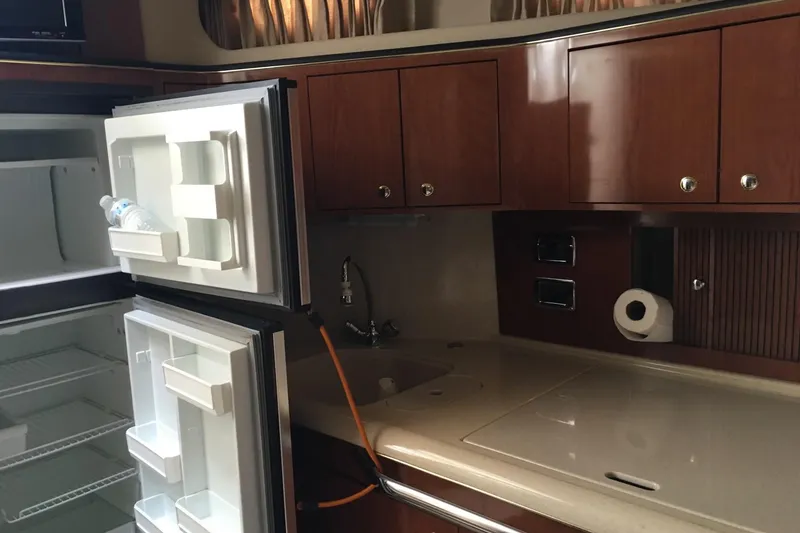 Slide: The Image of Interior of 2002 Sea Ray 410 Sundancer yacht kitchen with open fridge and wooden cabinets. - 10