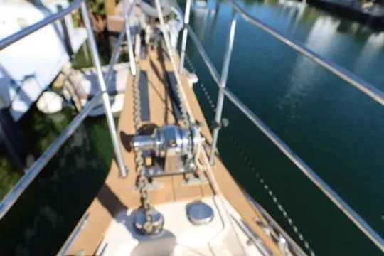 Slide: The Image of 1989 Island Packet 38 sailboat docked, featuring a covered deck and wind turbine. - 16