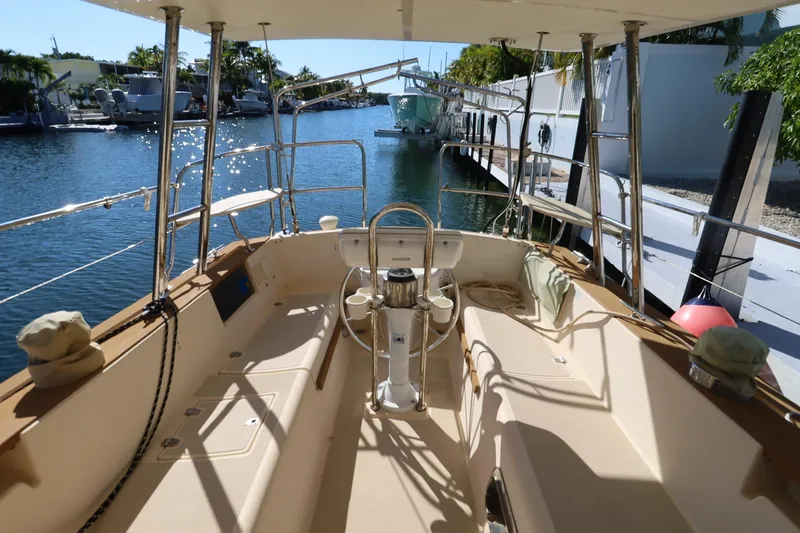 Slide: The Image of 1989 Island Packet 38 yacht interior with red bedding, wooden cabinetry, and compact bathroom. - 9