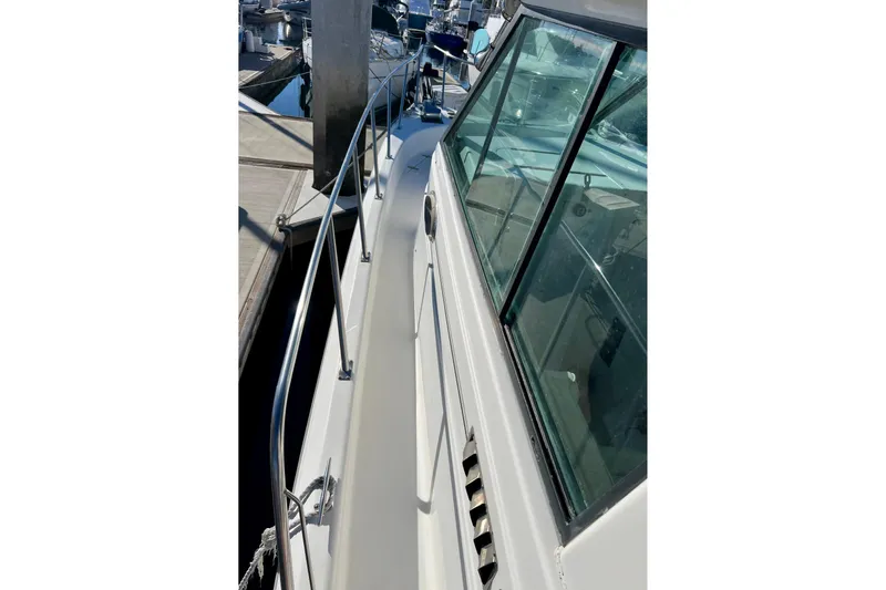 Slide: The Image of 1998 Baha Cruisers 340 CAT boat docked, showcasing side deck and windows. - 18