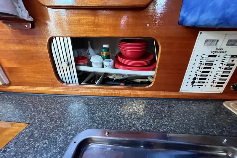 Slide: The Image of 1998 Baha Cruisers 340 CAT interior with storage, red dishes, and control panel. - 43