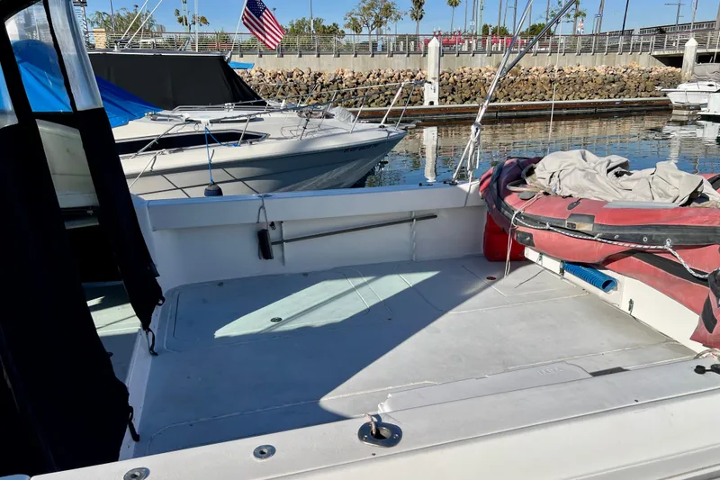 Slide: The Image of 1998 Baha Cruisers 340 CAT boat docked, featuring spacious deck and inflatable dinghy. - 7