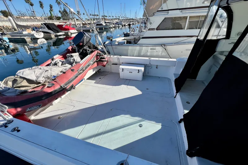 Slide: The Image of 1998 Baha Cruisers 340 CAT boat docked, featuring spacious deck and inflatable dinghy. - 8