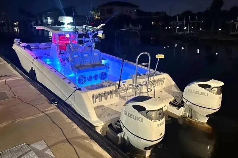 Slide: The Image of 2023 Twin Vee 340 GFX CC boat with blue interior lighting and Suzuki engines at night. - 12