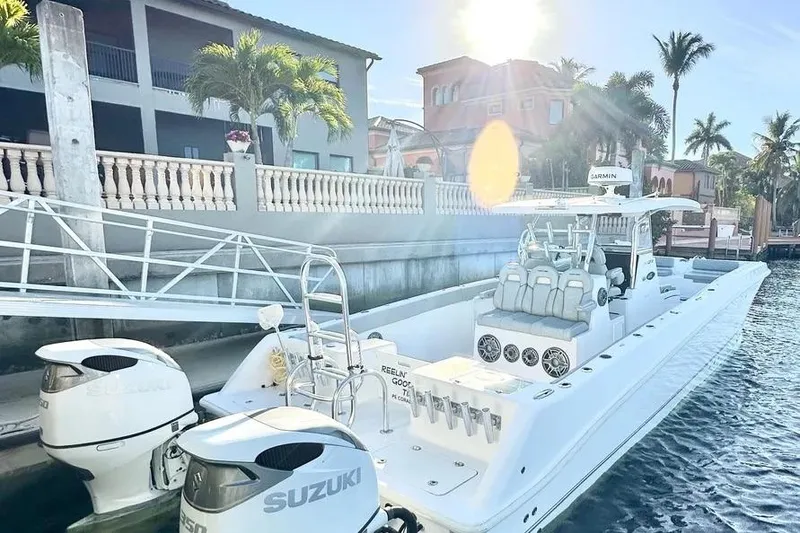 Slide: The Image of 2023 Twin Vee 340 GFX CC boat docked, featuring dual Suzuki engines, sunny waterfront setting. - 2
