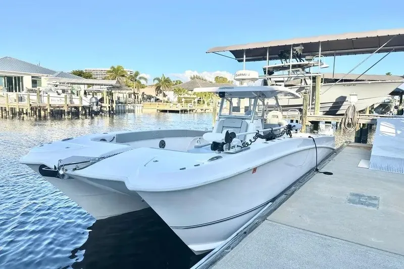 Slide: The Image of 2023 Twin Vee 340 GFX CC catamaran docked at a marina under clear blue skies. - 4