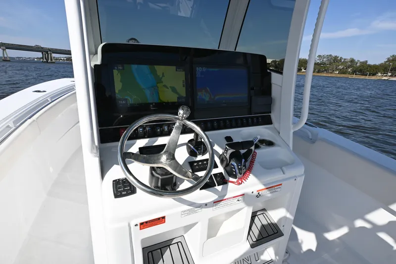Slide: The Image of 2024 Sea Hunt Gamefish 28 helm with dual displays and steering wheel on open water. - 9