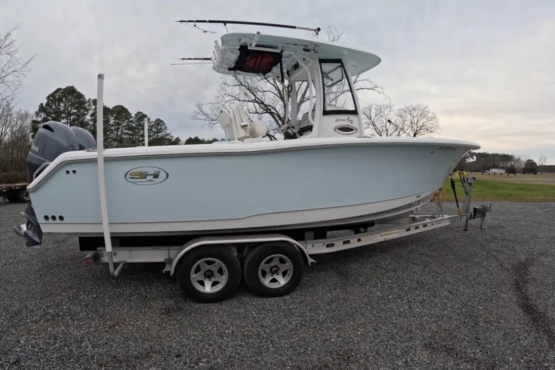 Slide: The Image of 2019 Sea Hunt Gamefish 25 boat on trailer, parked outdoors on gravel. - 1