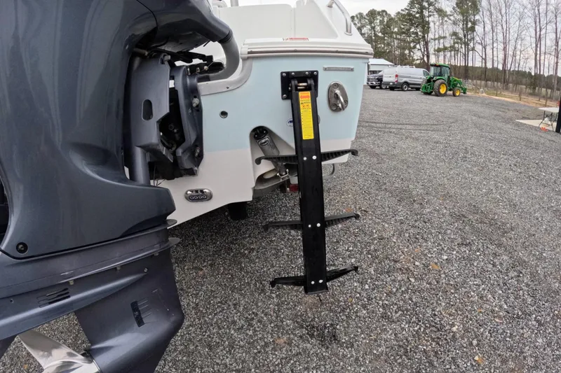 Slide: The Image of 2019 Sea Hunt Gamefish 25 boat with outboard motor and ladder on gravel surface. - 13