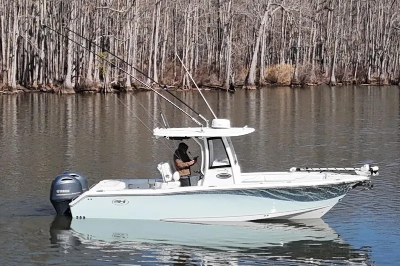Slide: The Image of 2019 Sea Hunt Gamefish 25 boat on calm lake with forest backdrop. - 16