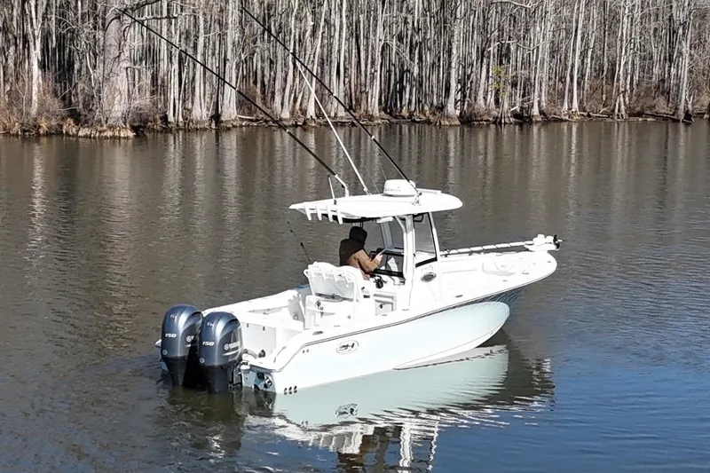 Slide: The Image of 2019 Sea Hunt Gamefish 25 boat on calm lake with forest backdrop. - 17