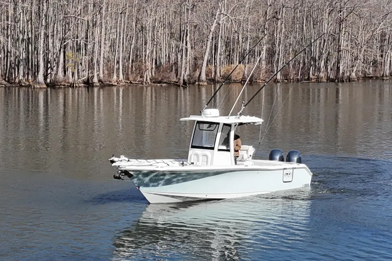 Slide: The Image of 2019 Sea Hunt Gamefish 25 boat cruising on a calm lake with forest backdrop. - 20